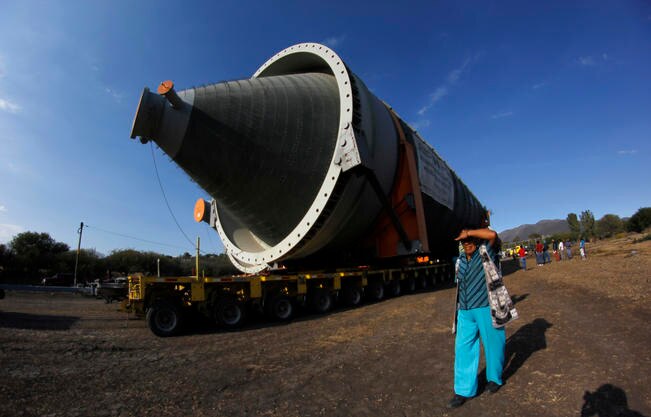 La gente de las comunidades se acerca con curiosidad a ver las calderas gigantes que son estacionadas a la vera del camino de terracería a la espera del anochecer, cuando pueden circular por la autopista. (LUIS SÁNCHEZ. EL UNIVERSAL)