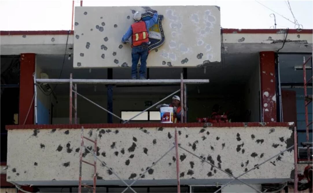 Trabajadores reparando la fachada del ayuntamiento, lleno de agujeros de bala, en Villa Unión, México. (AP Foto/Eduardo Verdugo)