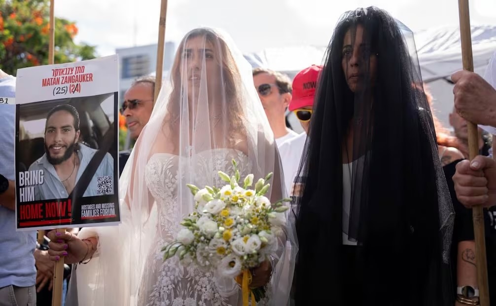 Con un cartel con la foto de su pareja, Matan Zangauker, quien se encuentra secuestrado por Hamas, Ilana Gritzewsky (izquierda) y su madre, Einav Zangauker, llegan a una ceremonia de boda simbólica en la plaza de los rehenes en Tel Aviv, Israel, el domingo 17 de agosto de 2025. Foto: AP