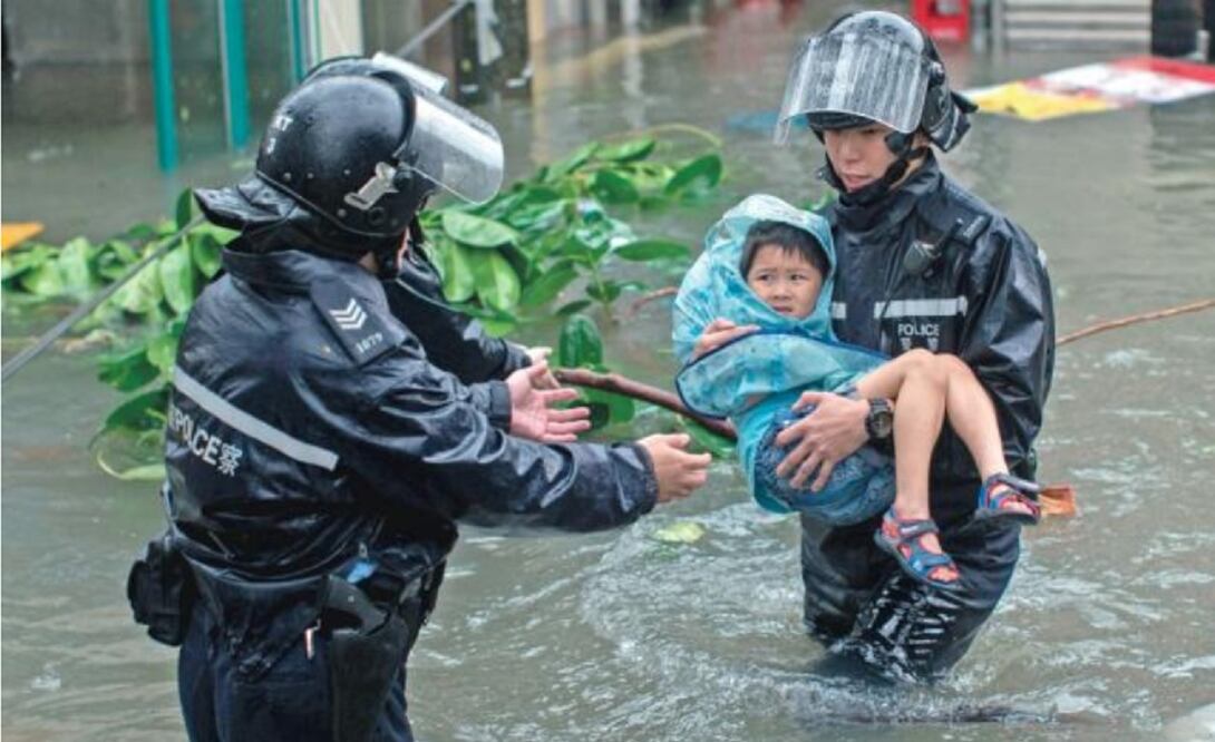 Policías rescatan a un niño en una calle inundada en el barrio de Lei Yu Mun, en Hong Kong, por el tifón Mangkhu t , que ha dejado unas 200 personas heridas a su paso por la ciudad. (JEROME FAVRE. EFE)