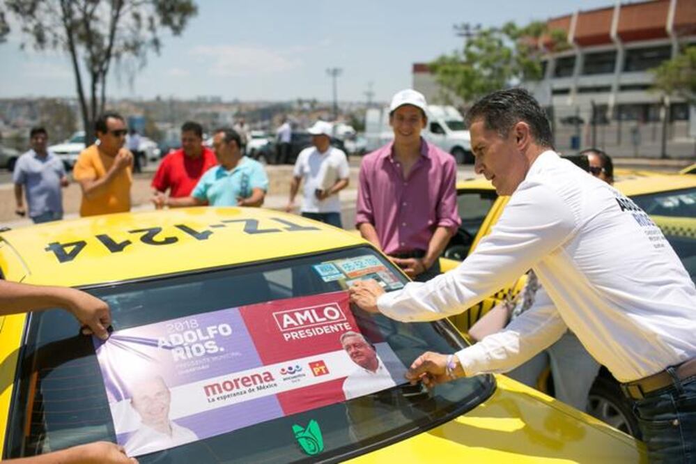 Luego de la plática los taxista participan junto a Adolfo Ríos en una actividad de pega de calcas en sus unidades de trabajo. Foto: Especial