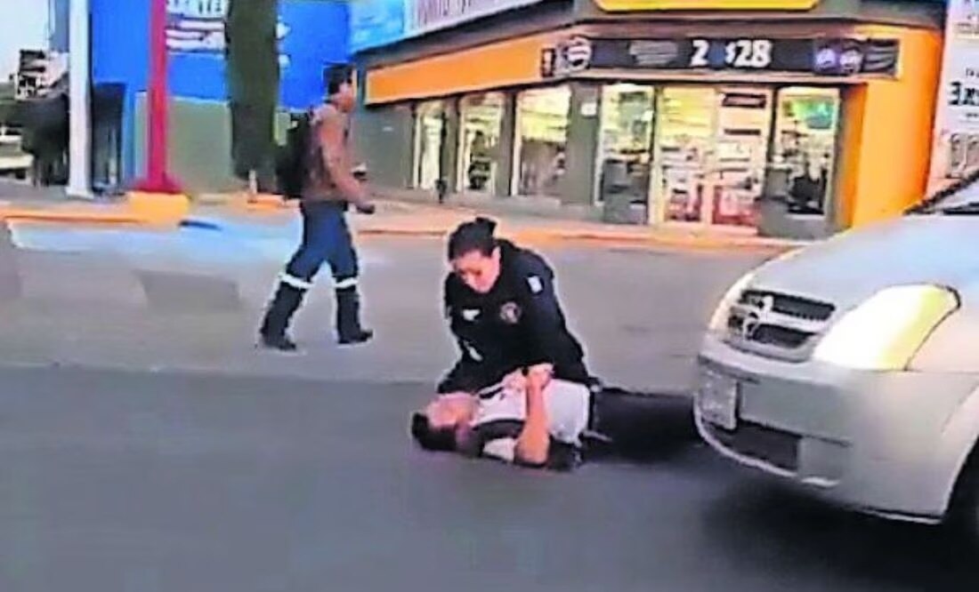 Una mujer policía trata de reanimar a su compañero baleado por dos civiles armados; el elemento murió en el hospital. Foto: Especial