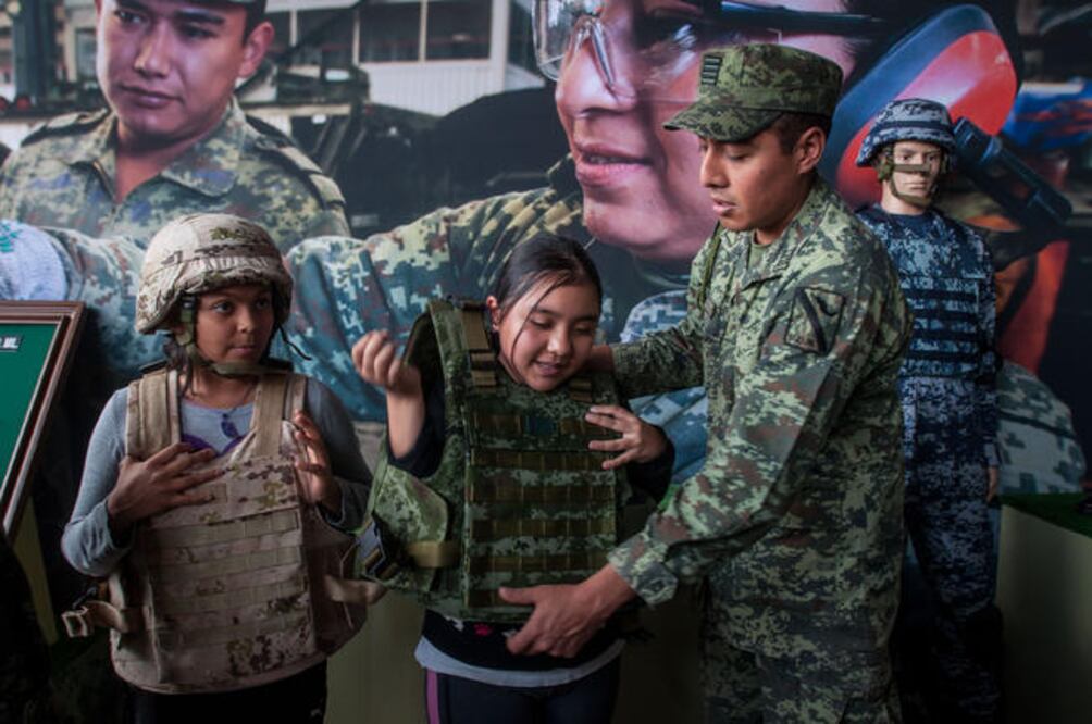 Un par de niñas se visten con cascos y chalecos balísticos con ayuda de soldados que, amablemente, les colocaban los aditamentos militares, para luego posar a su lado para la foto (RICARDO LUGO. EL UNIVERSAL)