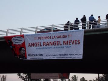 Cuelgan ex policías mantas en puente