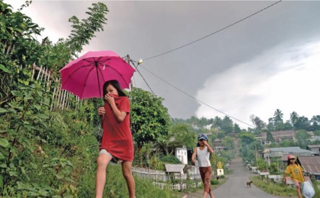 Lugareños se cubren la boca después de que el volcán Soputan hiciera erupción ayer, en la localidad indonesia de Kota Menara. (REUTERS)