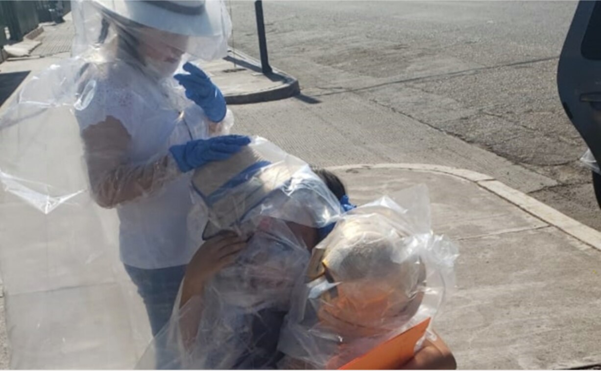 Cubiertas en trajes de plástico, niñas sorprenden con regalos a su madre enfermera