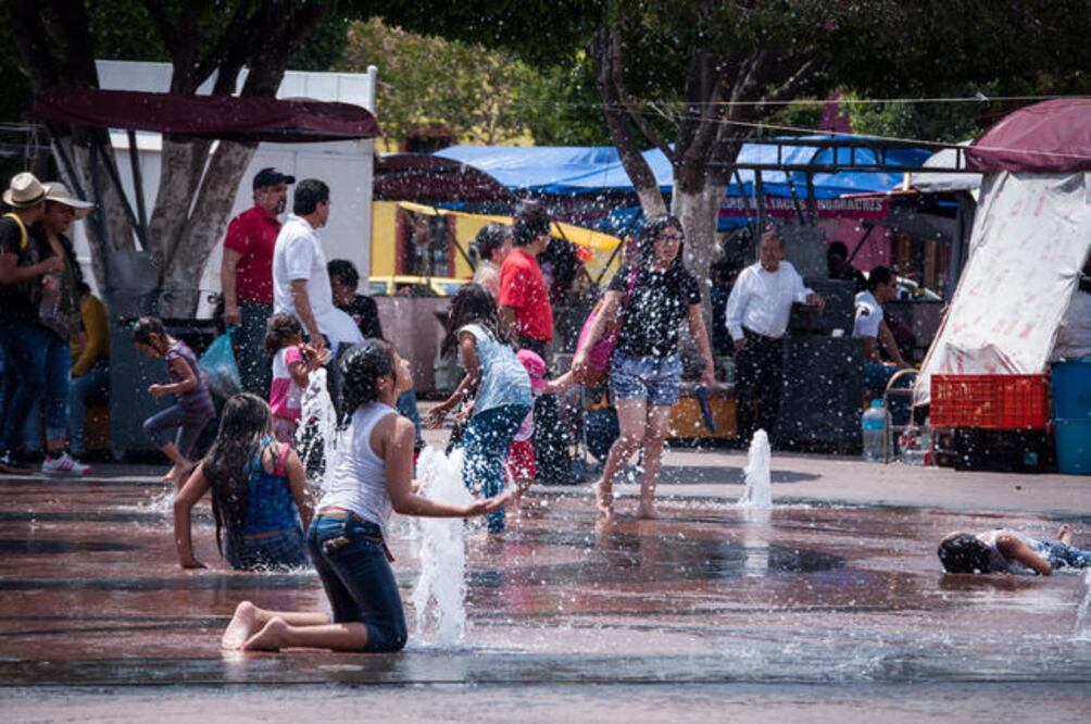 Los padres de familia que se rehusarían en otro día para cumplir el deseo de los pequeños de mojarse en la fuente que brota del piso, los dejan jugar sin ninguna restricción (LUIS SÁNCHEZ)