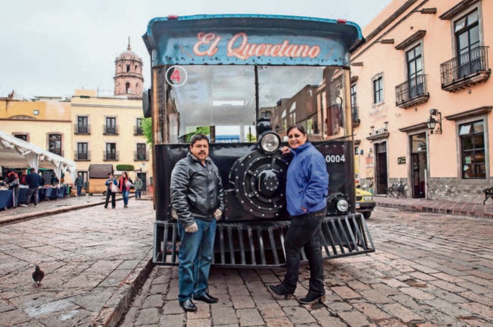 Frente al jardín Corregidora Tamara González, guía, y Juan Jesús López, conductor del tranvía, esperan a paseantes nacionales y extranjeros para llevarlos por un viaje de una hora en el que pueden disfrutar de la ciudad de Querétaro (RICARDO LUGO)