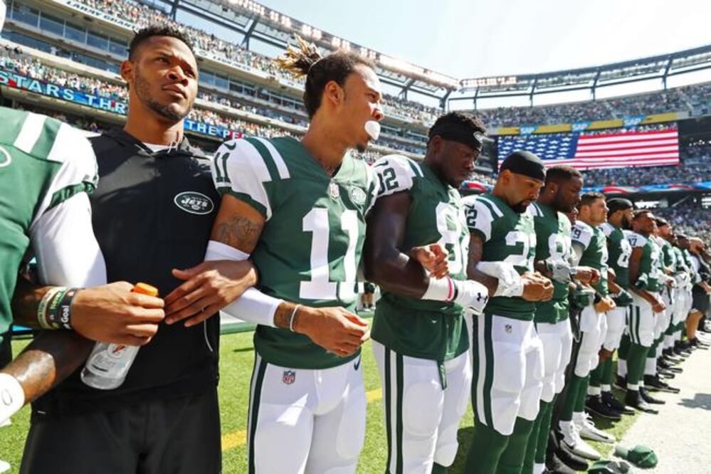 Jugadores de Jets permanecieron de pie, pero con los brazos unidos al interpretarse el himno nacional, en el MetLife Stadium, previo al juego contra Dolphins (AL BELLO. AFP)