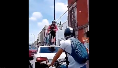 Ciclista pasa por encima de automóvil; obstruía su paso 