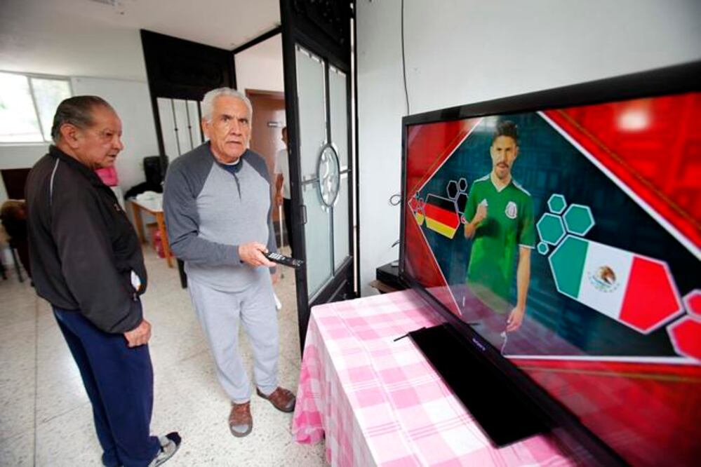 Pedro y otros de sus compañeros del albergue aprovechan la visita de un grupo de estudiantes, quienes distraen a las mujeres, para apoderarse del control de la televisión y ver los partidos del mundial de futbol. / Foto: Guillermo González