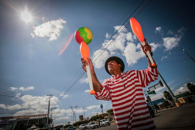Para llamar la atención de los conductores, Fernando silba música de circo para que su público observe como lanza cuatro clavas hacia el cielo. Llega a ganar 100 pesos por hora (DEMIÁN CHÁVEZ)