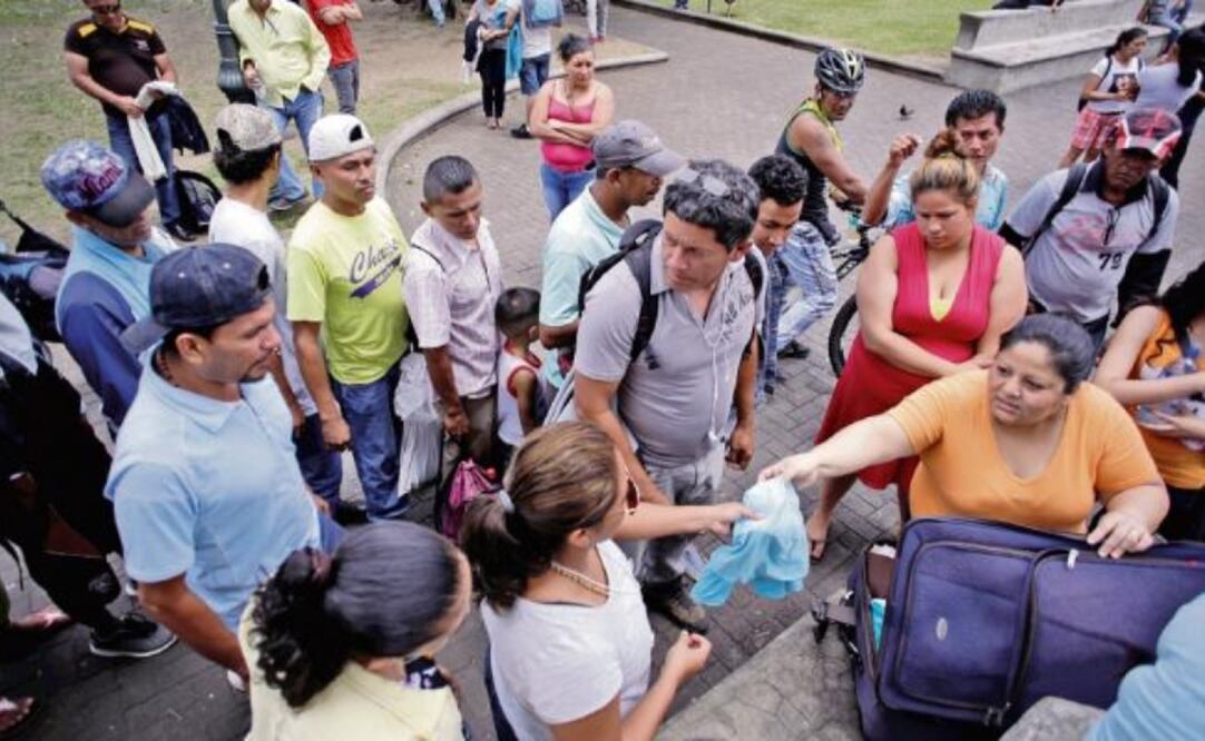 Una mujer distribuye ropa a nicaragüenses que huyeron de la violencia en su país y llegaron a San José, la capital costarricense (JUAN CARLOS ULATE. REUTERS)