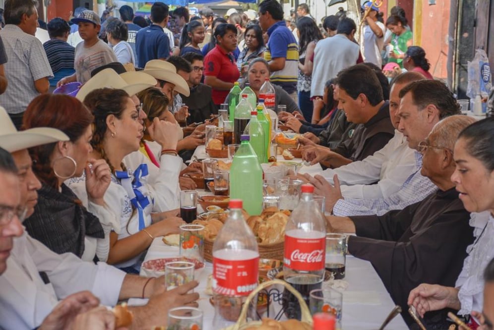 La calle de Cuauhtémoc se convierte en un gran comedor al aire libre. Hombres vestidos de pantalón de mezclilla, camisa blanca y una cinta roja a la cintura, terminan de colocar lonas para proteger a los comensales